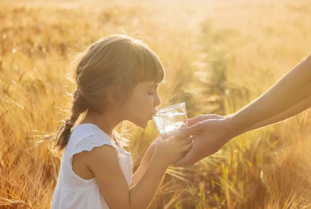Petite fille qui boit un verre d'eau